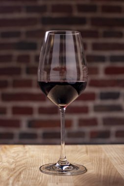 Kırmızı yarı tatlı üzüm doğal ahşap bir masa bir restoranda lezzetli bir zarif cam kadeh şarapta duruyor. Akşam yemeği için harika bir ilave