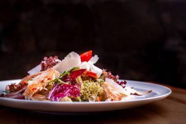 Bir restoranda siyah arka planda bir salata kase Cesar salata