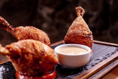 Üç tane tavuk bacağı var. siyah arduvaz üzerinde dur. Siyah arka plan, güzel ışık.