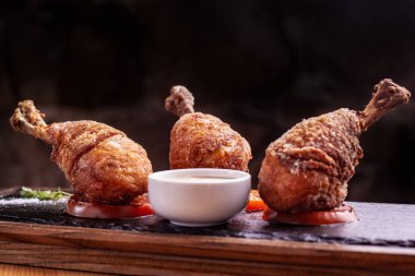 Üç tane tavuk bacağı var. siyah arduvaz üzerinde dur. Siyah arka plan, güzel ışık.