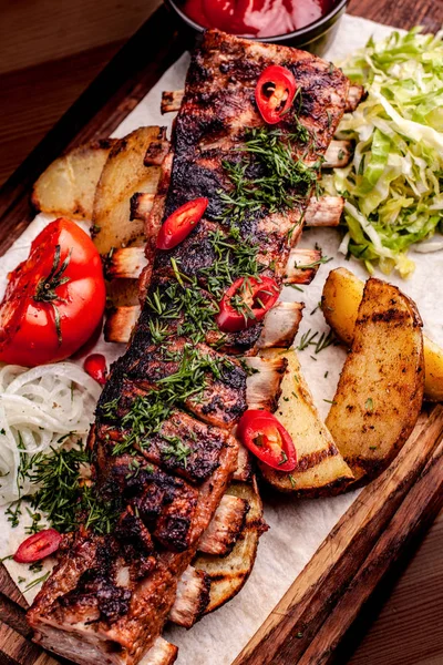 Heerlijke gegrilde ribben gekruid met verse kruiden, Koolsalade, gesteunde aardappel op een oude rustieke houten snijplank — Stockfoto