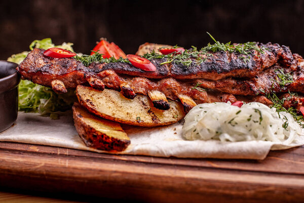 Delicious barbecued ribs seasoned with fresh herbs, cabbage salad, backed potato on an old rustic wooden chopping board