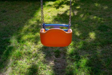 Bahçede turuncu zincir salıncak. Yaz. Arkadan görüntüle. 