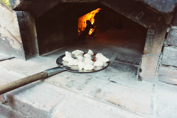 stock image Small dough balls on paddle ready to bake. Homemade small breads are getting into stone oven.