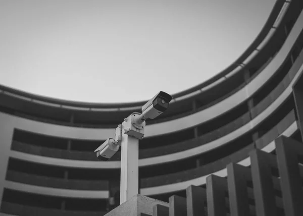 Security camera in public area. Black and white image of street security cameras with the building in the background.