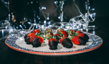 Çilek plaka üzerinde çikolata ile kaplı ve ışıkları ile dekore edilmiştir. Çilek hizmet vermeye hazır yakın görüntü.