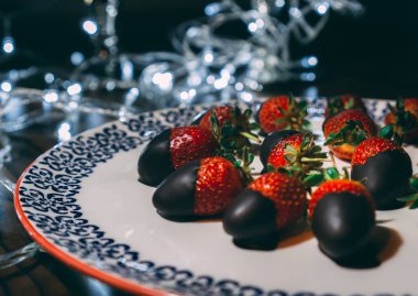 Çilek plaka üzerinde çikolata ile kaplı ve ışıkları ile dekore edilmiştir. Çilek hizmet vermeye hazır yakın görüntü.