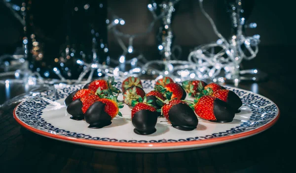 Çilek plaka üzerinde çikolata ile kaplı ve ışıkları ile dekore edilmiştir. Çilek hizmet vermeye hazır yakın görüntü.