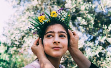 Çiçek çelenk giyen güzel bir küçük kız portresi.