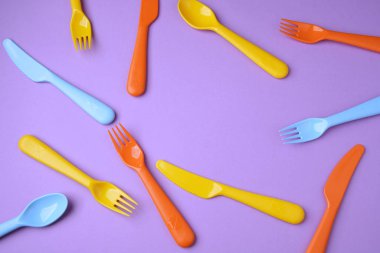 Birçok renkli plastik çatal, kaşık ve bıçak Menekşe backgrou üzerinde