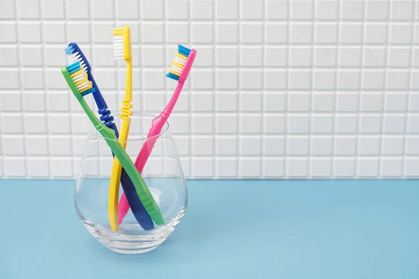 Cepillos de dientes en taza de vidrio en el baño —  Fotos de Stock