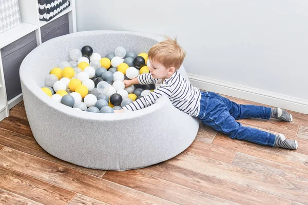 Chico jugando con pelotas en la piscina de su habitación. Interior nórdico —  Fotos de Stock