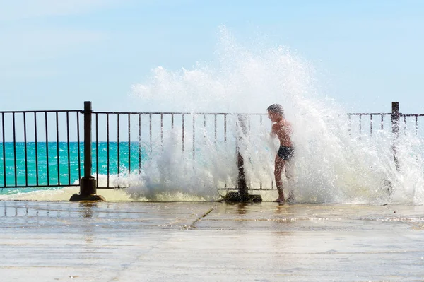 Menino brincando nas ondas fora do cais — Fotografia de Stock