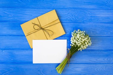 Tekne zarflar, beyaz boş Not kartı ve Vadideki Zambak buketi. mockup. Üstten görünüm ve düz lay kopya alanı ile.