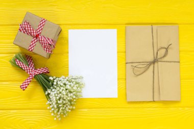 Bahar sarı arka plan. Taze çiçekler, zarf, hediyeler, tebrik kartı ambalaj. düz yatıyordu, en iyi görünümü