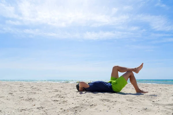 Joven disfrutando de unas vacaciones, acostado con las piernas en la orilla del mar , — Foto de Stock