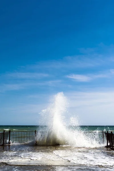 Sea water splashes at old pier on sunny day — Stock Photo, Image