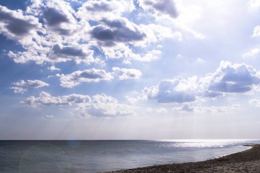 Bulutlu gökyüzü karşı parlak gün batımı sırasında deniz kıyısı.