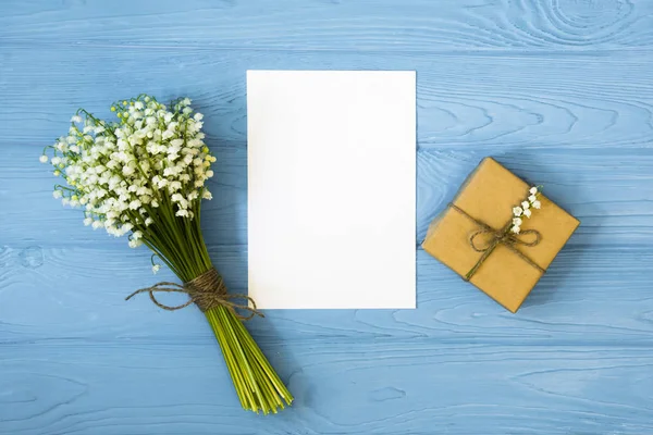 Mockup with bouquet and empty greeting card, gift box top view, copy space for text, flat lay