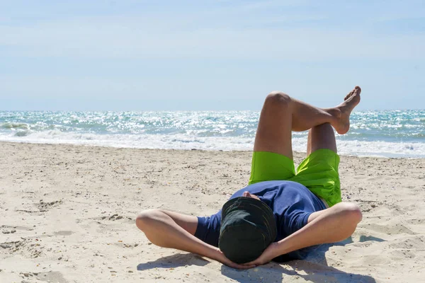 Jeune homme voyageur avec chapeau sur le visage dormir avec bonheur et détente sur la belle plage . — Photo