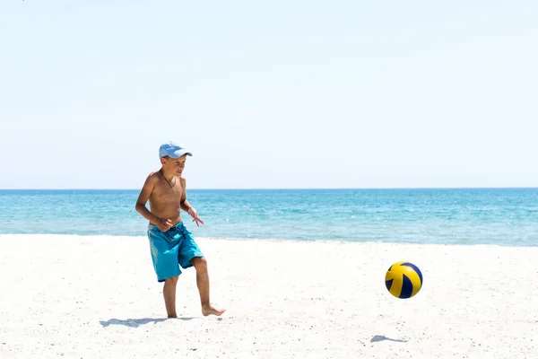 Мальчик играет в футбол на пляже — стоковое фото