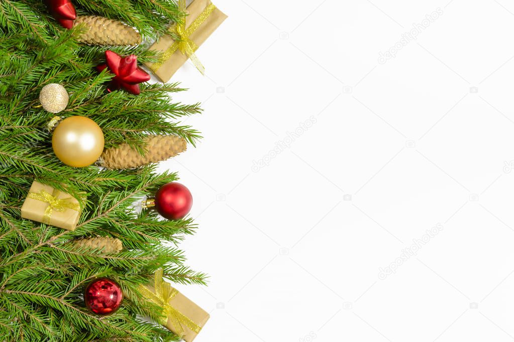 Christmas border isolated on white, composed of fresh fir branches, cones and ornaments in red and gold
