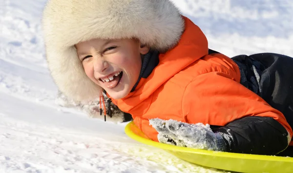 Um menino sorrindo deitado em seu Sled, close-up retrato. Diversão de inverno — Fotografia de Stock