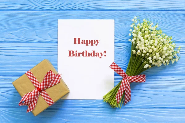 Happy Birthday greeting card and flowers on wooden background
