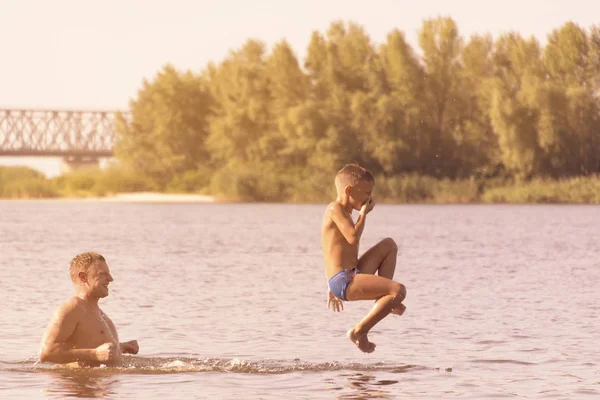 Sauter dans l'eau. Homme et garçon s'amusent et éclaboussent dans l'eau. Concept vacances d'été. tonique — Photo