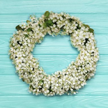 Yuvarlak kare çelenk bahar çiçekleri ve yaprakları mavi ahşap zemin üzerine yapılmış. Düz yatıyordu. Üstten görünüm.