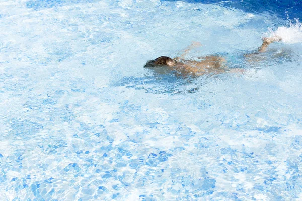 Мальчик затаил дыхание под водой в солнечном бассейне. Обучение плаванию — стоковое фото