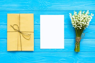 Tekne zarflar, beyaz boş Not kartı ve Vadideki Zambak buketi. mockup. Üstten görünüm ve düz lay kopya alanı ile.