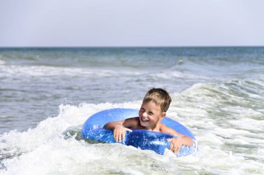 Şişme halka üzerinde bir deniz dalgası sürme Çocuk