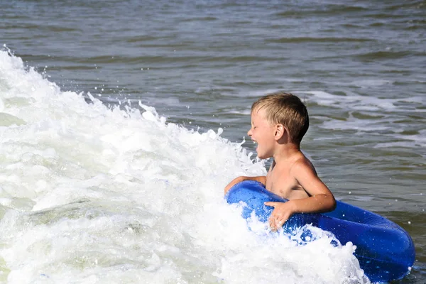 Chłopiec jeździ morską falą na nadmuchiwanym pierścieniu — Zdjęcie stockowe