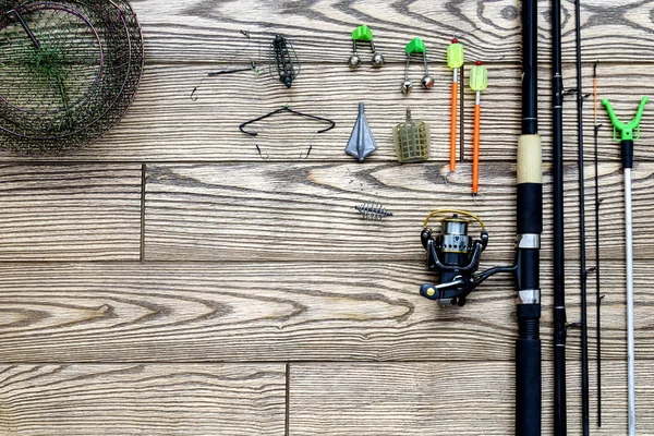 Fishing feeder and reel.Fishing tackle background.Fishing feeder- hooks and lures on darken wooden background. — Stock Photo, Image