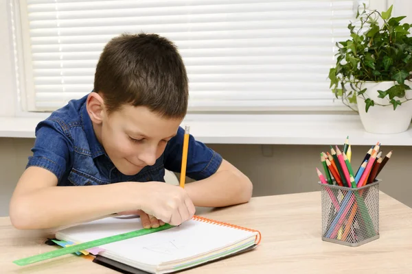 De loting van de jongen in de laptop. Kind zit aan het bureau thuis en zijn huiswerk. School, kinderen, onderwijs concept — Stockfoto