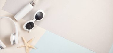 Üstten görünüm temel yaz aksesuar güneş gözlüğü, kulaklık ve pastel arka plan üzerinde güneş kremi