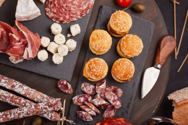 Meze tablo değişik antipasti, peynir, charcuterie, aperatifler ve şarap ile. Mini Burgerler, sosis, jambon, tapas, zeytin, peynir çeşitli kurul ve baget üzerinde gri arka plan beton. Üstten görünüm, düz yatıyordu