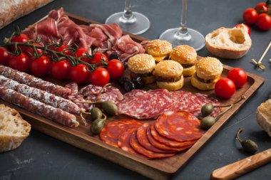 Meze tablo değişik antipasti, peynir, charcuterie, aperatifler ve şarap ile. Mini Burgerler, sosis, jambon, tapas, zeytin, peynir çeşitli kurul ve baget üzerinde gri arka plan beton. Üstten görünüm, düz yatıyordu