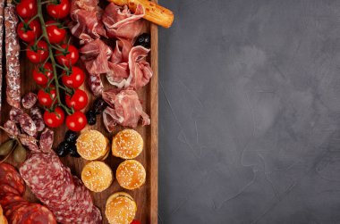 Meze tablo değişik antipasti, peynir, charcuterie, aperatifler ve şarap ile. Mini Burgerler, sosis, jambon, tapas, zeytin, peynir çeşitli kurul ve baget üzerinde gri arka plan beton. Üstten görünüm, düz yatıyordu