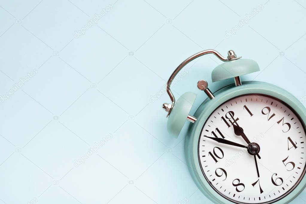 Retro style alarm clock over the pastel blue background