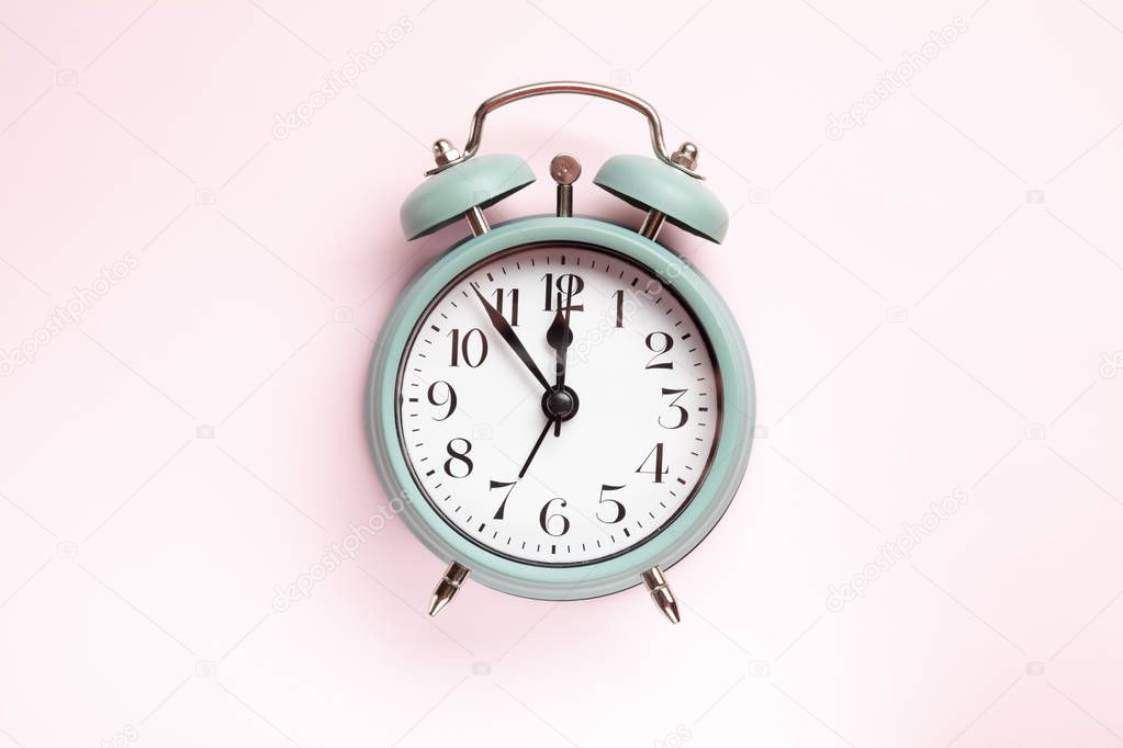 Retro style alarm clock over the pastel pink background