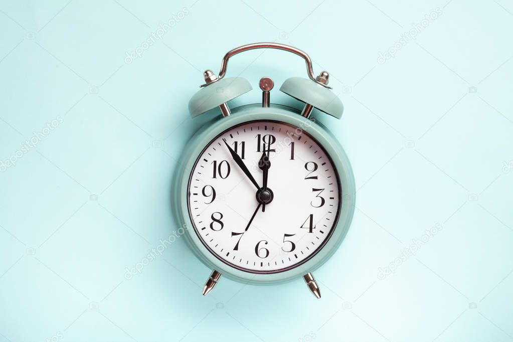 Retro style alarm clock over the pastel blue background