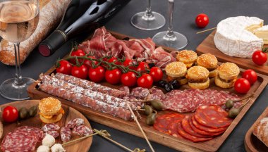 Meze tablo değişik antipasti, peynir, charcuterie, aperatifler ve şarap ile. Mini Burgerler, sosis, jambon, tapas, zeytin, peynir ve baget üzerinde gri arka plan beton. Üstten görünüm, düz yatıyordu