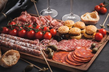 Meze tablo değişik antipasti, peynir, charcuterie, aperatifler ve şarap ile. Mini Burgerler, sosis, jambon, tapas, zeytin, peynir çeşitli kurul ve baget üzerinde gri arka plan beton. Üstten görünüm, düz yatıyordu