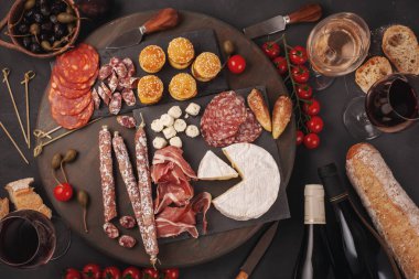 Meze tablo değişik antipasti, peynir, charcuterie, aperatifler ve şarap ile. Mini Burgerler, sosis, jambon, tapas, zeytin, peynir ve baget üzerinde gri arka plan beton. Üstten görünüm, düz yatıyordu