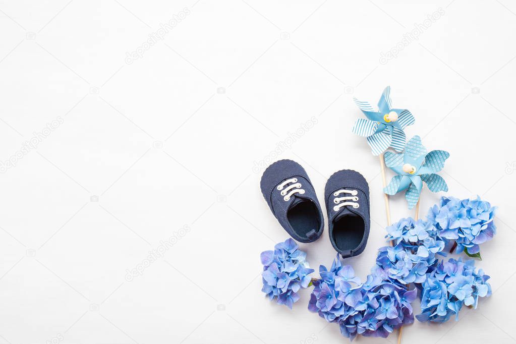 Cute newborn baby boy shoes with festive decoration over the white background. Baby shower, birthday, invitation or greeting card mockup