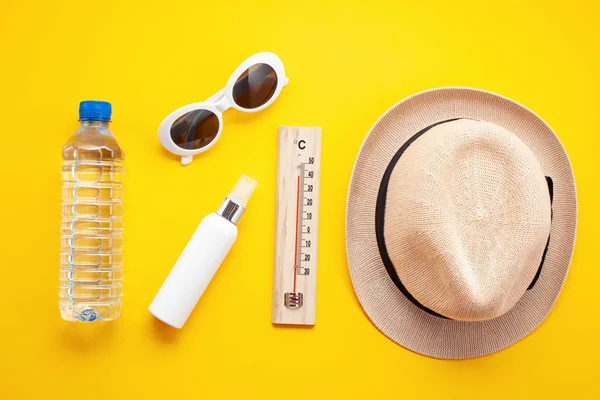 Essential accessories for summer heat: sunglasses, hat, sunscreen and bottle of water. Flat lay, top view