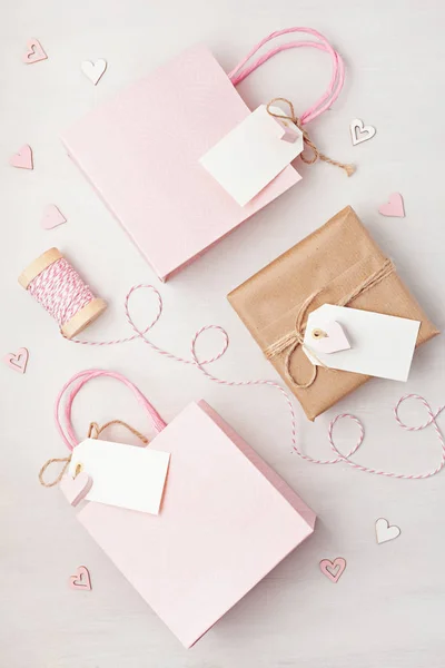 Creative image of gift bag and box with empty tag, heart and christmas decorations in pink pastel colors