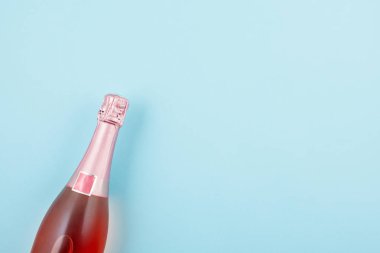 Şampanya şişesi mavi zemin üzerine konfeti ile yaratıcı fotoğraf. Düz yatıyordu yılbaşı, yıldönümü, yeni yıl kutlama kavramı